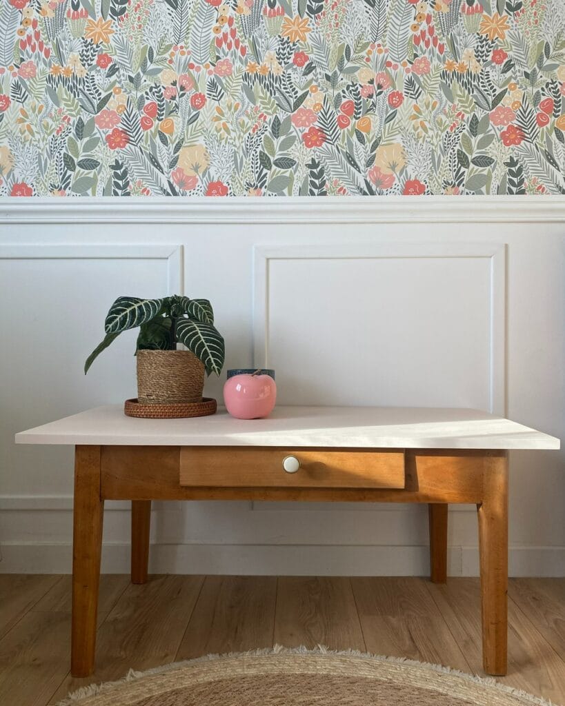 Table basse ancienne rénovée en hêtre, avec plateau peint et structure aérogommée et vernie, dans un intérieur clair.