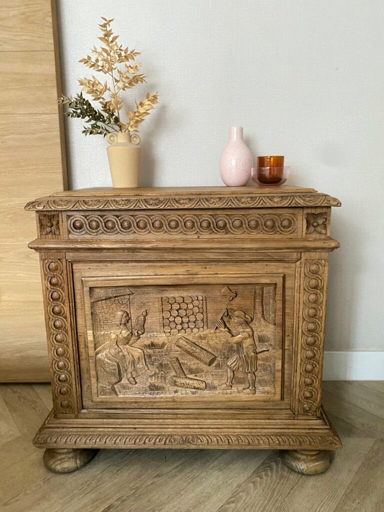 Armoire bretonne en chêne massif après décapage par aérogommage, révélant des sculptures détaillées de fileuse et bûcheron.