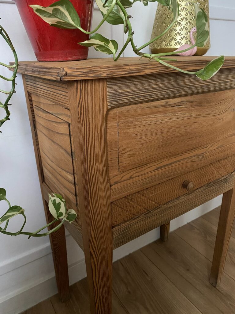 Chevet ancien en pin restauré avec finition bois brut. Le décapage révèle les détails sculptés du tiroir et la couleur miel du bois. — photo 2